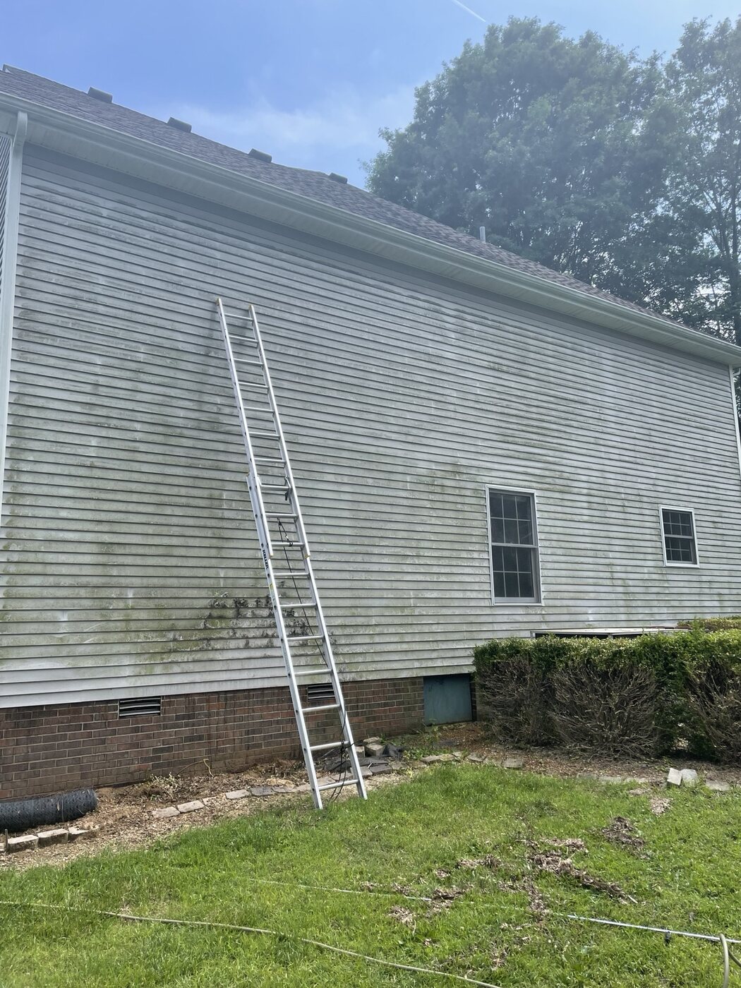 Two-story house siding with heavy dirt and organic buildup before soft washing