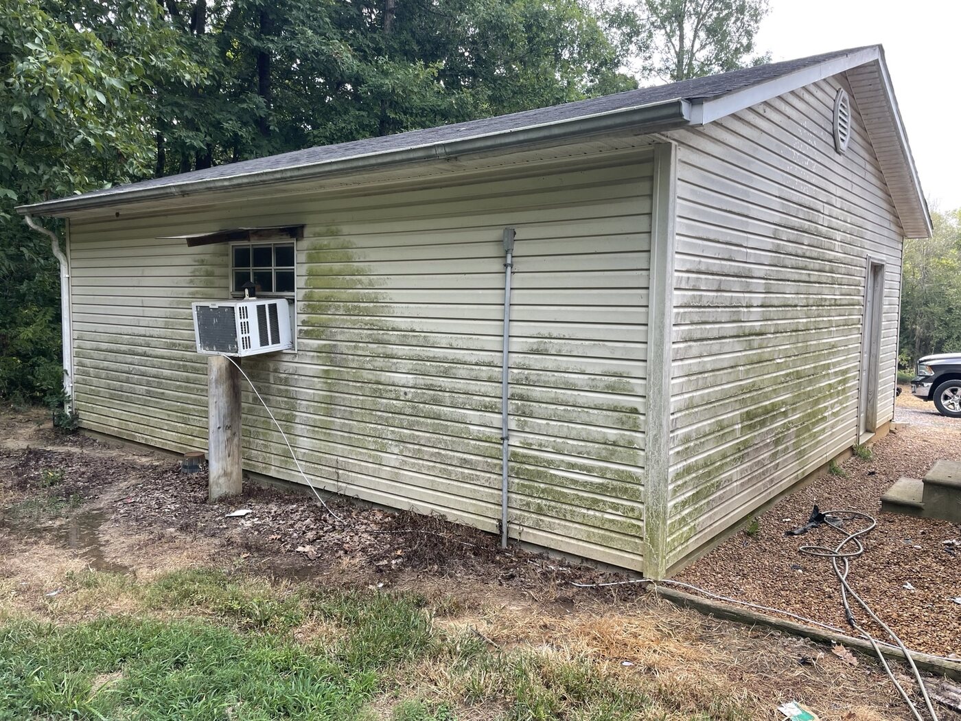 Garage siding covered in green organic growth before soft washing
